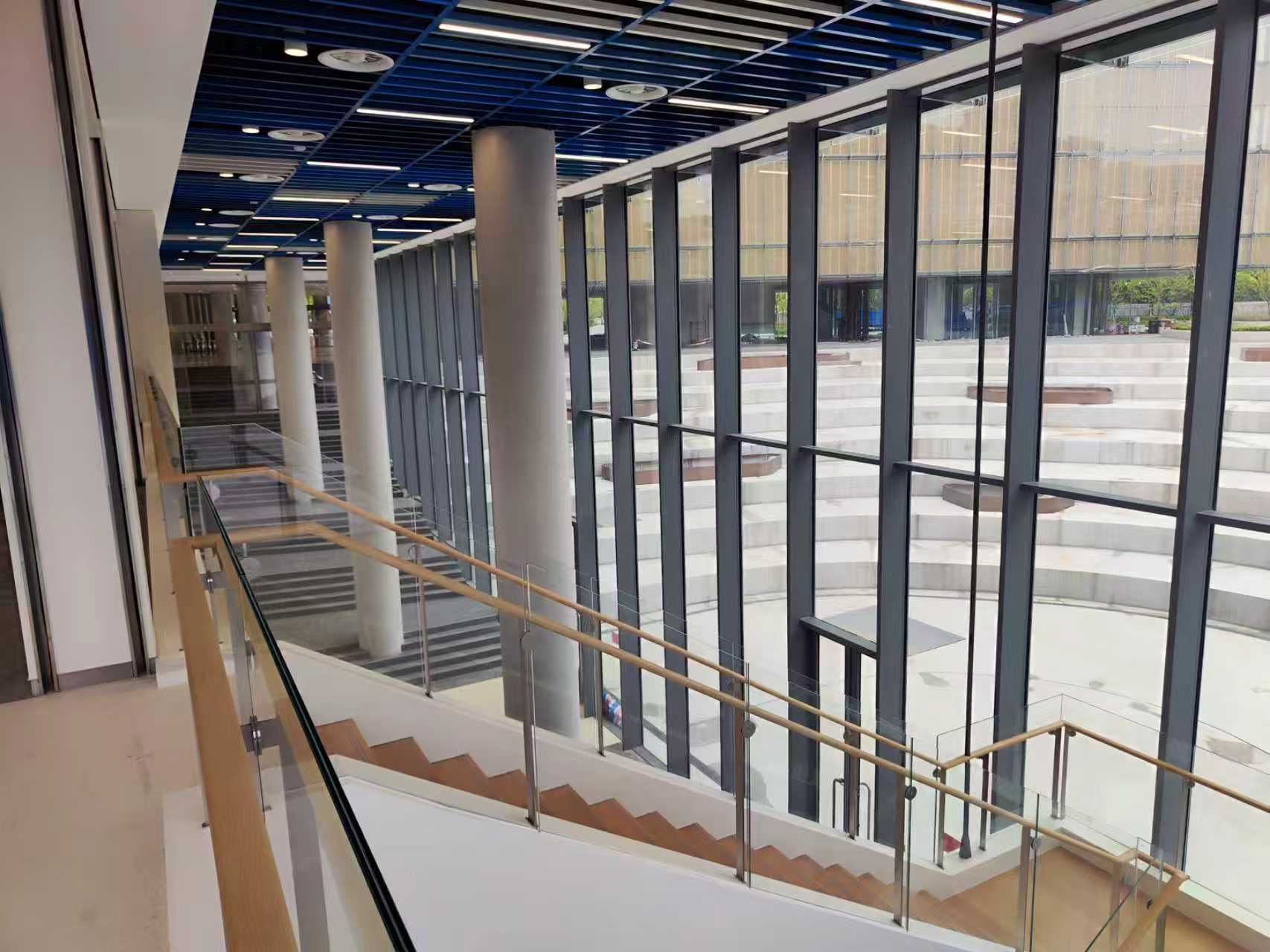 Interior stair and circulation space beside a full-height glazed curtain wall