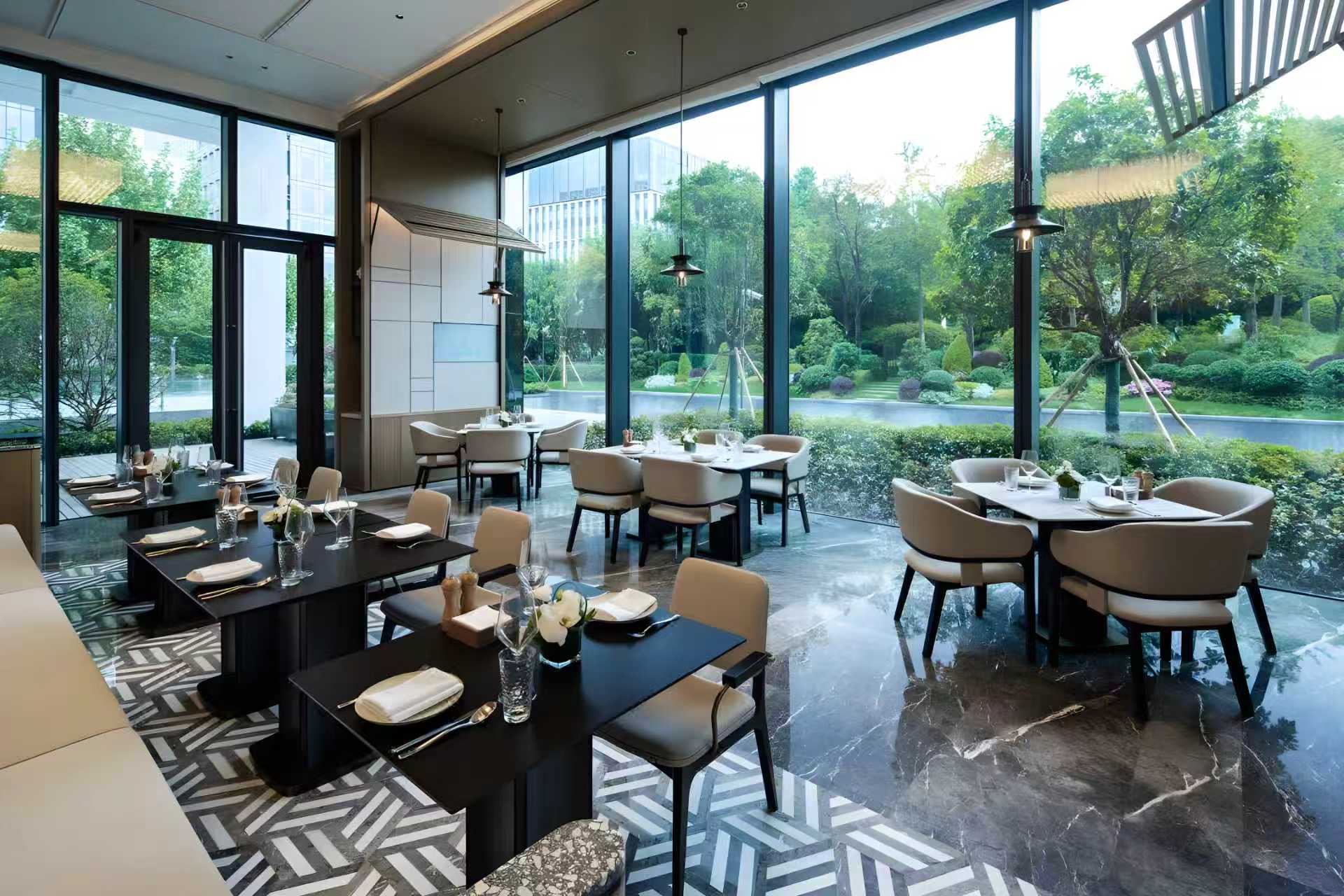 Hospitality interior with full-height architectural glazing overlooking landscaped gardens